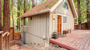 Una cabaña con terraza de madera, puerta principal y un pequeño porche.