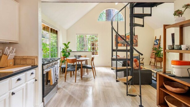 Una cocina moderna con armarios blancos, encimera de madera y un comedor con mesa y sillas.