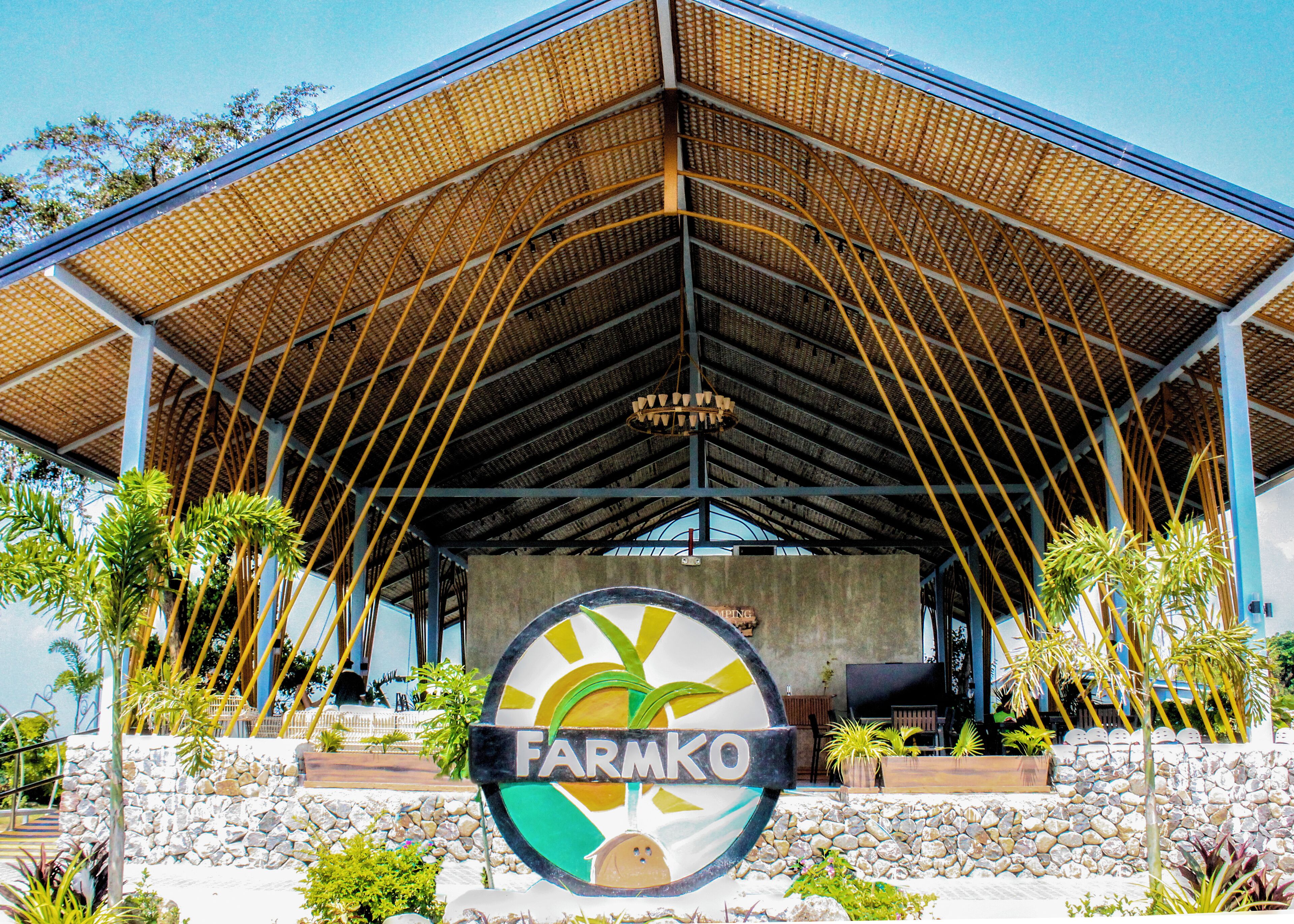 Un bâtiment sur lequel est apposée une grande enseigne portant le nom « Farmko », et une zone abritée avec un toit incurvé soutenu par des poutres jaunes.