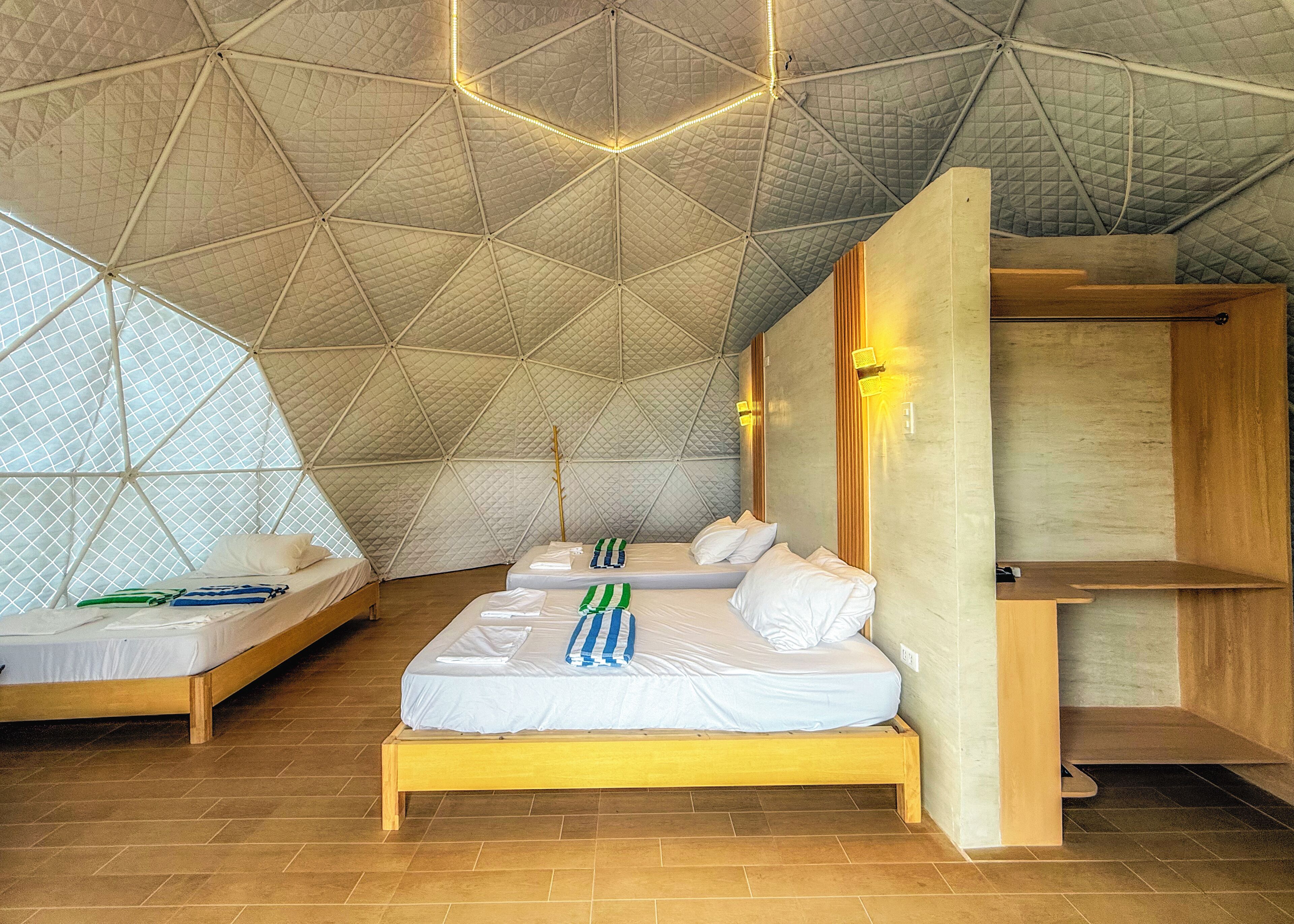 A room with a geometric ceiling, wooden beds, and a small wooden table.