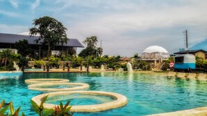 A swimming pool with circular water features, surrounded by greenery and a clear sky. - FarmKo Glamping (Dolores)