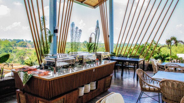 A restaurant with a buffet setup, outdoor seating, and a view of greenery and distant buildings. - FarmKo Glamping (Dolores)