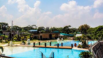 Una piscina con sillones de descanso, una fuente de agua y vistas de edificios y zonas verdes circundantes.