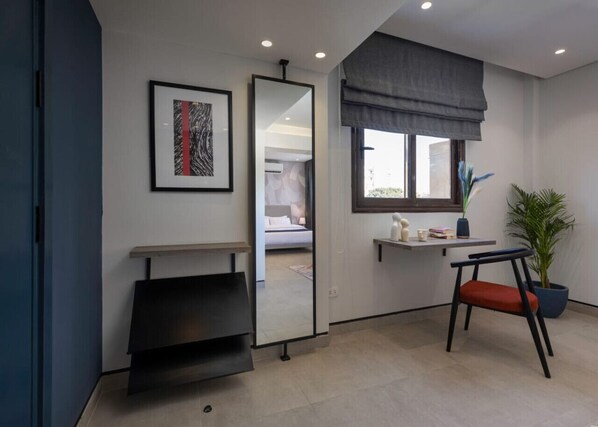 A modern room with a bed, a mirror, a small table with a plant, and a chair.