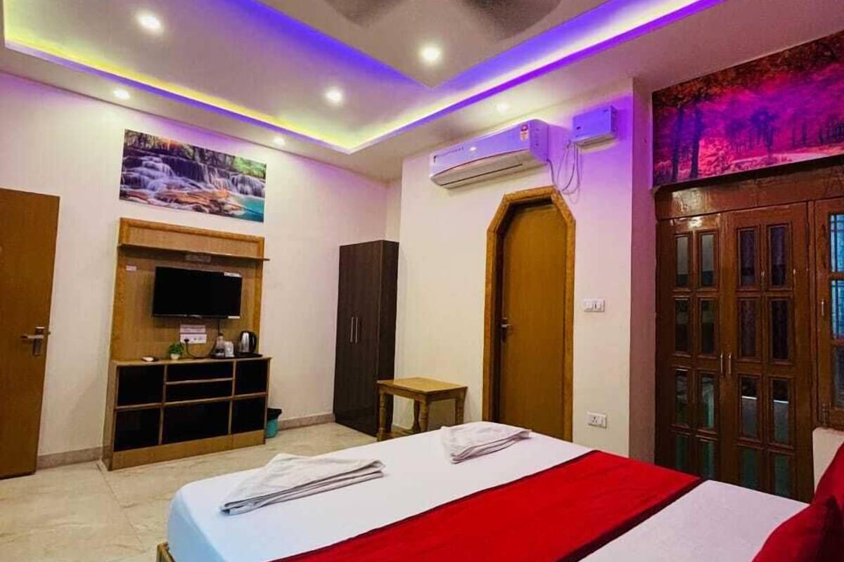Ein Hotelzimmer mit einem Bett, einem Deckenventilator, einer Klimaanlage, einem an der Wand montierten Fernseher und einer Tür mit Holzpaneelen.