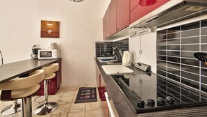 A compact kitchen with a microwave, kettle, and stove.