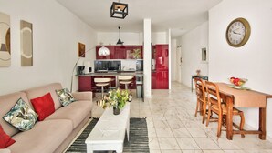 A modern living room with a sofa, coffee table, and dining area with chairs and a table.