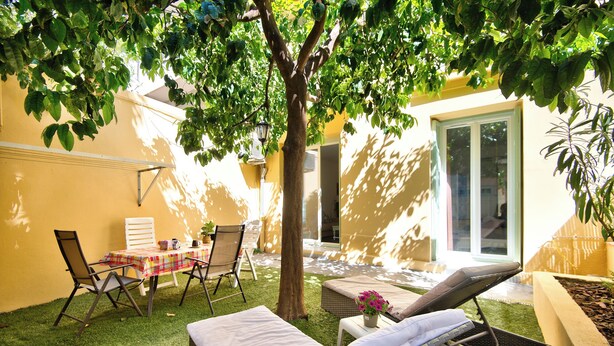 A sunlit outdoor seating area with a table, chairs, and lounge chairs.