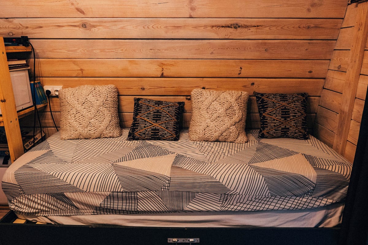 Ein Zimmer in einer Holzhütte mit einem Bett, ausgestattet mit geblümter Bettwäsche und vier Kissen.
