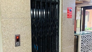 A modern elevator with a digital display, a security gate, and a reception desk. - Hotel Churu Palace (Jaipur)