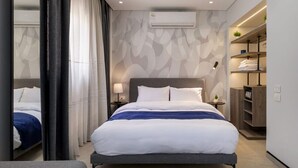A modern hotel room with a large bed, bedside tables, an air conditioning unit, and a built-in wardrobe.