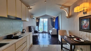 A modern kitchen with a dining area, featuring a long counter, a dining table set for two, and a view through to a living room. - Grand Florida 1Bedroom CloseToBeach G610 (Sattahip)