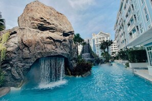 Een hotel met een grote rotsformatie, een waterval en een zwembad.