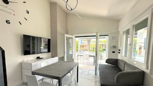 Una cocina moderna con televisión, una mesa de comedor con sillas y un sofá.