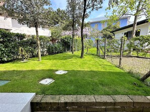 Ein gepflegter Garten mit Rasenfläche, Bäumen und einem Stacheldrahtzaun.