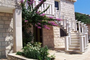 A stone building with a white staircase and a balcony. - Two Bedroom Apartment (Povlja)