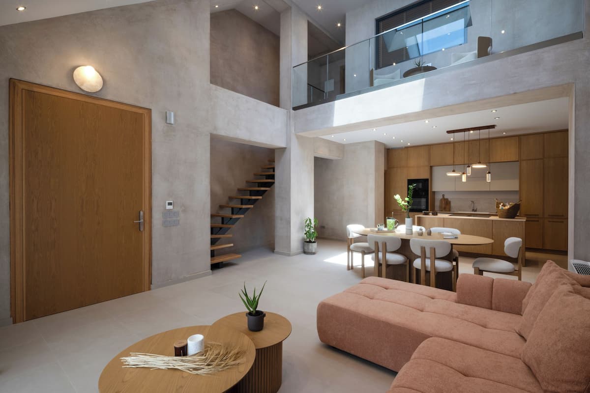 A modern interior with a staircase, a dining area, and a living room with a sofa and coffee table.