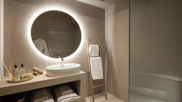 A modern bathroom with a round mirror, a sink, and a towel rack.