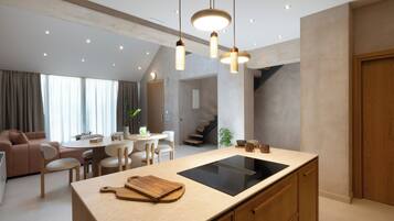 A modern kitchen with an island, pendant lights, and a dining area with a sofa and chairs.