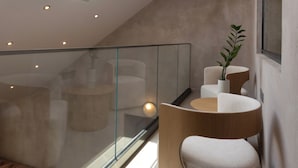 Un intérieur moderne agrémenté d’une verrière, d’une balustrade en verre et de mobilier contemporain.