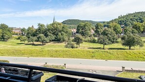 Une vue d’une ville avec un clocher d’église imposant, des champs verdoyants et des immeubles d’habitation.