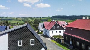 Una zona residencial con casas de techos rojos y grises, un cielo azul despejado y colinas verdes al fondo.