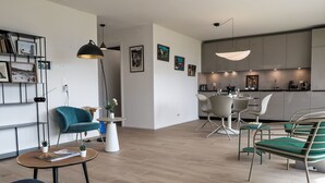 A modern living room with a sofa, a coffee table, and a dining area with chairs.