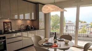A modern kitchen with a dining area, large windows, and a view of the city.