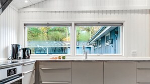 Een moderne keuken met een groot raam, een inbouwoven en een spoelbak.