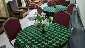 A dining area with round tables covered in green checkered tablecloths, red chairs, and white flowers in vases. - Otakef Motel  (Arusha)