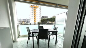 A balcony with a table and chairs, a view of a building, and a body of water. - Apartment With Pool Near the Beach (San Michele al Tagliamento)
