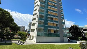 A multi-story residential building with balconies, a central staircase, and a surrounding green area. - Apartment With Pool Near the Beach (San Michele al Tagliamento)