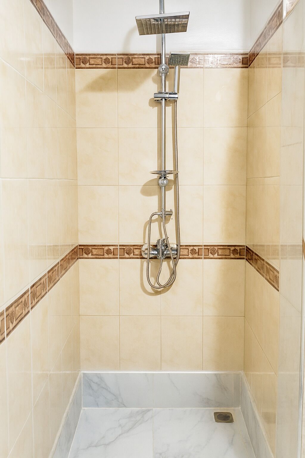 A shower with a handheld showerhead, a fixed showerhead, and a handheld shower attachment.
