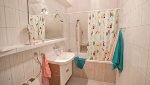 Un baño con lavamanos, espejo, ducha y bañera.