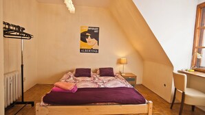 Un dormitorio con cama, escritorio, silla, radiador y un cartel en la pared.