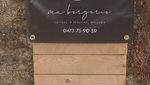 A wooden sign with the number '18B' and a black plaque below it with the text 'Mabergie COTTAGE IN BEAUTIFUL WALLONIA' and a phone number. - Tiny cottage in beautiful Wallonia (Sombreffe)