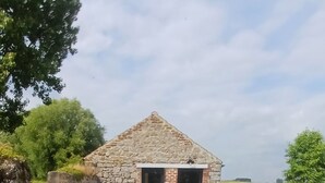 A stone building with a wooden fence in front, surrounded by greenery. - Tiny cottage in beautiful Wallonia (Sombreffe)