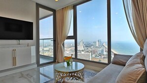 A modern living room with a large window, a flat-screen TV, a sofa, and a small table with a vase. - CopacabanaJomtien Condo PrivatePool CBJ1 (Pattaya)