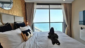 A hotel room with a large bed, a TV, and a view of the sea. - CopacabanaJomtien Condo PrivatePool CBJ1 (Pattaya)