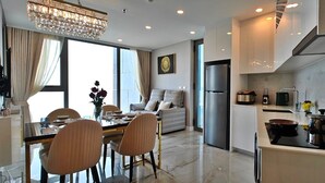 A modern kitchen with a refrigerator, stove, and dining area with chairs and a table. - CopacabanaJomtien Condo PrivatePool CBJ1 (Pattaya)