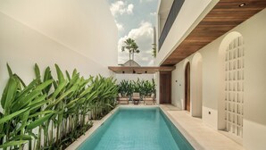 A swimming pool with a wooden ceiling, surrounded by plants and a seating area. - The Vinava Villa Canggu by Ini Vie Hospitality (Canggu)