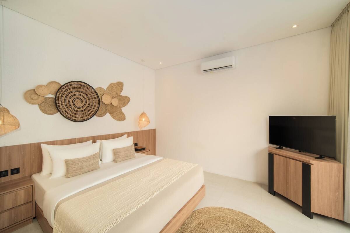Ein modernes Schlafzimmer mit einem Bett, einem Fernseher und einer Wandklimaanlage.
