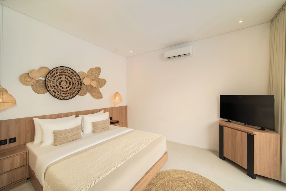 Ein modernes Schlafzimmer mit einem großen Bett, einem Flachbildfernseher und einer Wandklimaanlage.