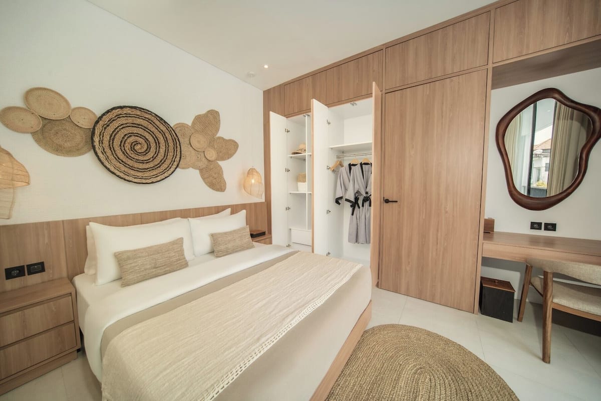 Ein Schlafzimmer mit Bett, Nachttischen, einem Kleiderschrank, einem Schreibtisch und einem Spiegel.