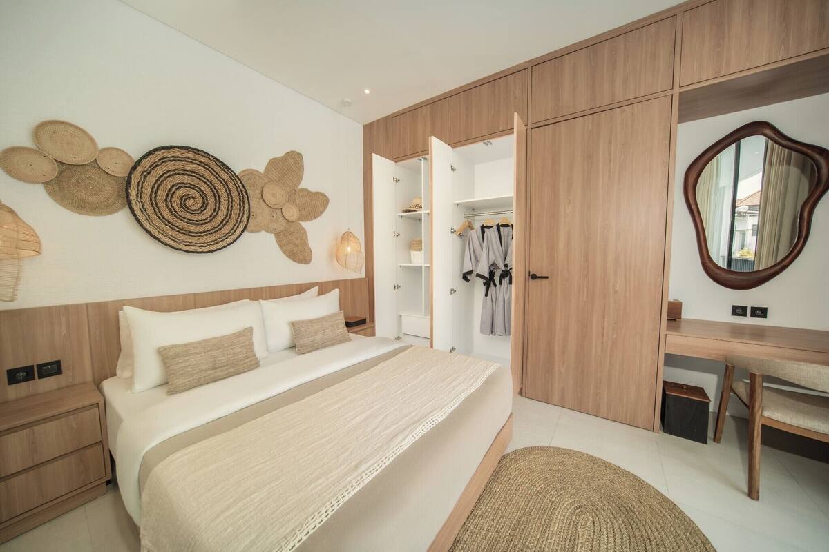 A bedroom with a bed, bedside tables, a wardrobe, a desk, and a mirror.