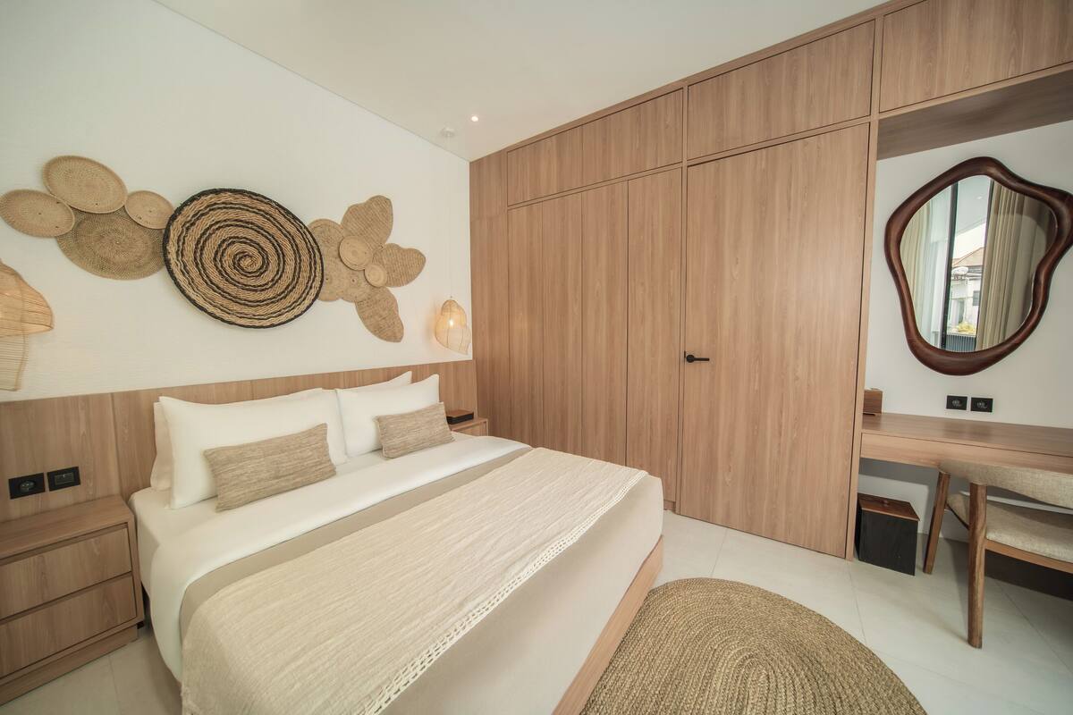 Ein modernes Schlafzimmer mit einem großen Bett, einem Holzschrank und einem Schreibtisch mit Spiegel.