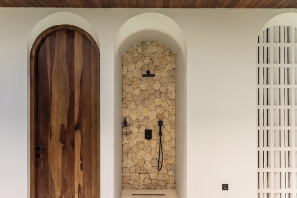 A wooden door, a stone wall with a shower, and a white grille. - The Vinava Villa Canggu by Ini Vie Hospitality (Canggu)