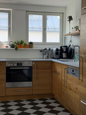 A kitchen with a Bosch oven, wooden cabinets, a checkered floor, and a window with a view.