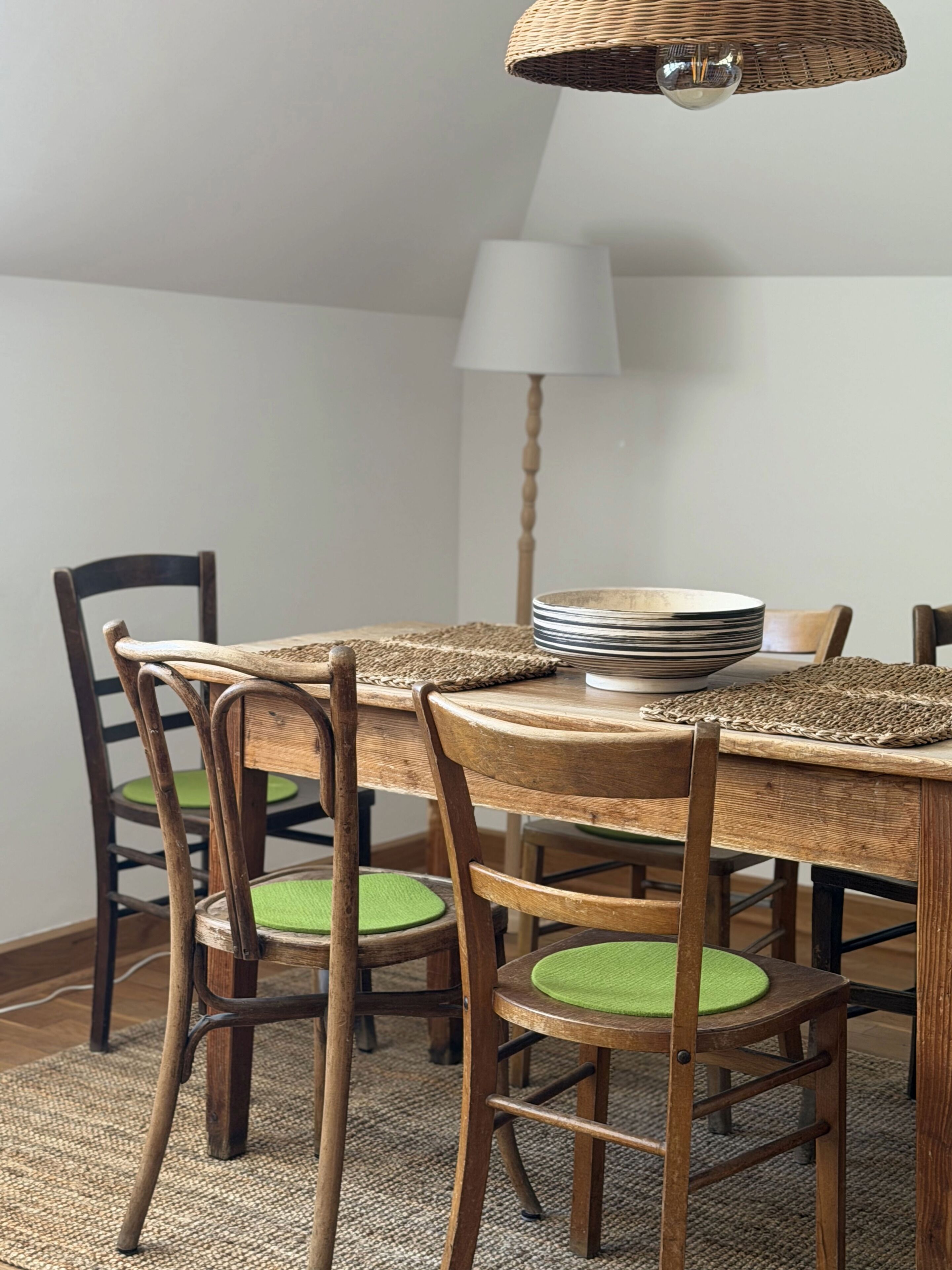A dining table with chairs, a lamp, and a stack of plates.