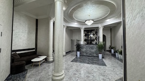 A lobby with marble flooring, a reception desk, a chandelier, and a seating area with sofas and a coffee table. - art home (Tashkent)